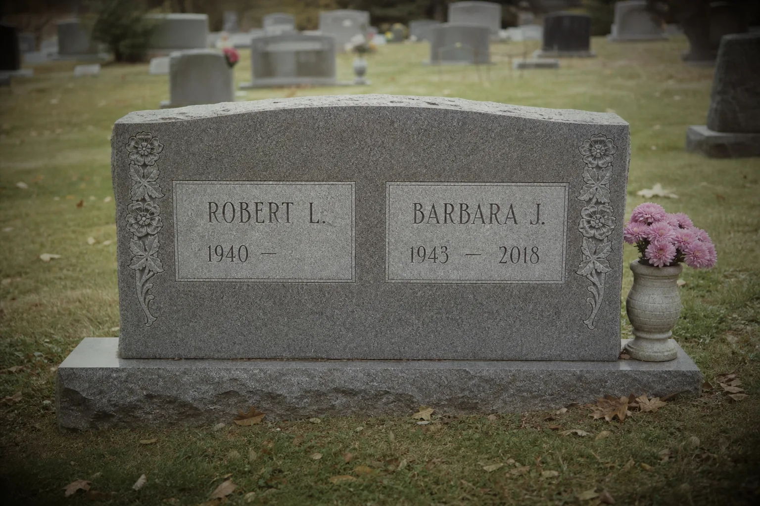 A granite companion headstone in a cemetery with two names inscribed side by side, one side showing a birth year followed by a blank space where a death date...