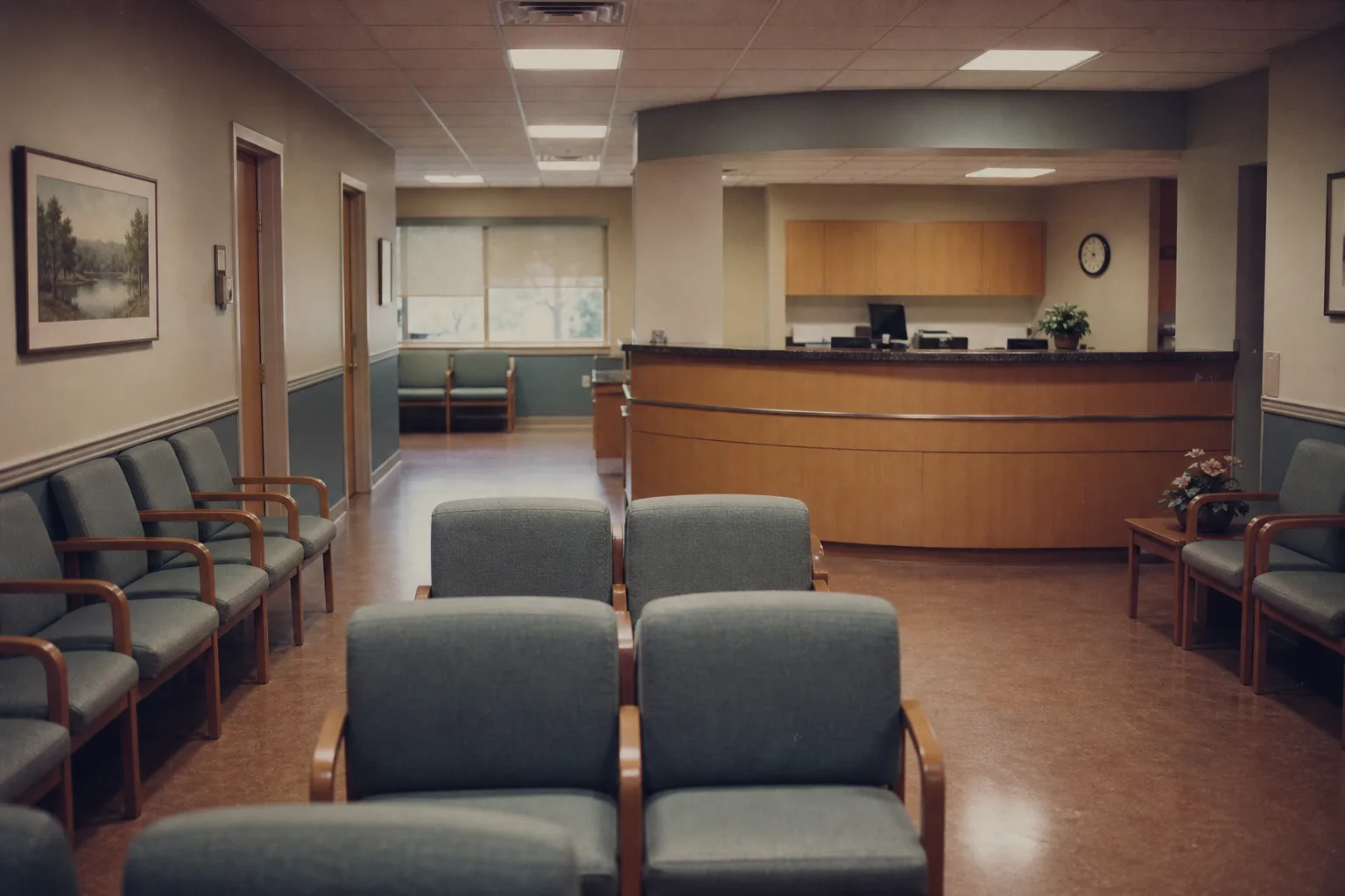 An urgent care clinic waiting room with empty chairs and a reception desk at the far end